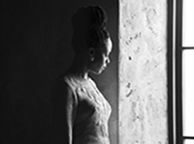 Moses Ingram as Lady Macduff in profile looking out a window with the wall in dark shadow behind her (black and white photograph).