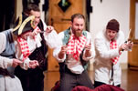 The four stooges, Franville wearing a 19th century admirals hat, kneel with knives and forks and red-checkered napkins tucked in their collars